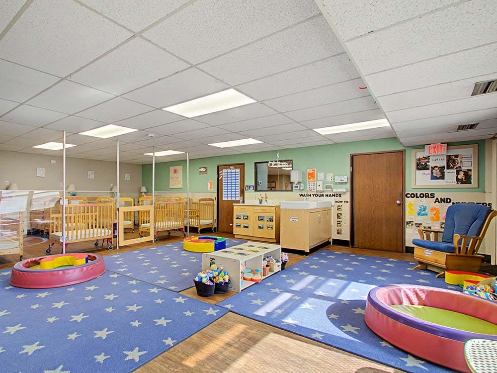 empty daycare room with cribs and playmats