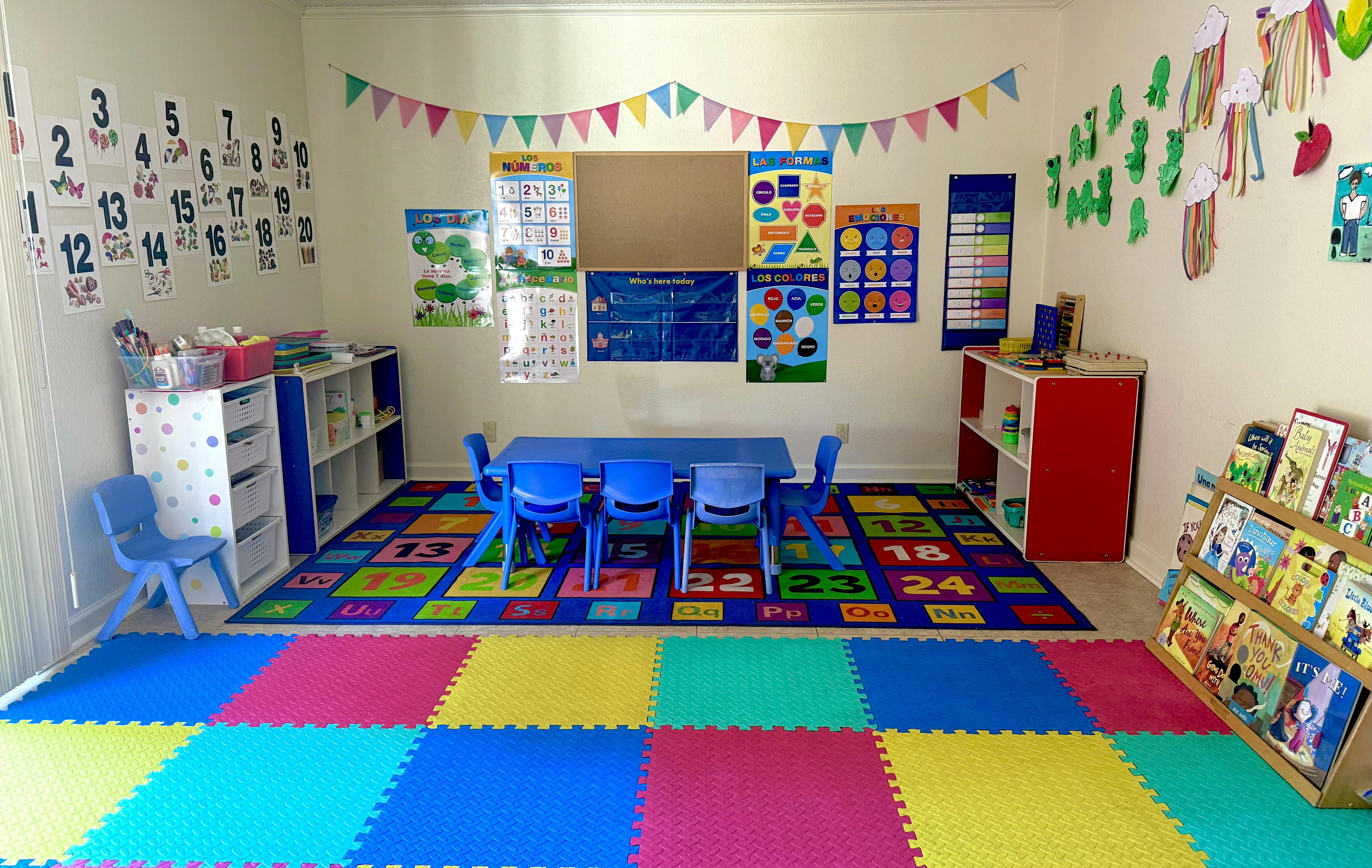 Classroom interior with small blue chairs around a table on a colorful rug