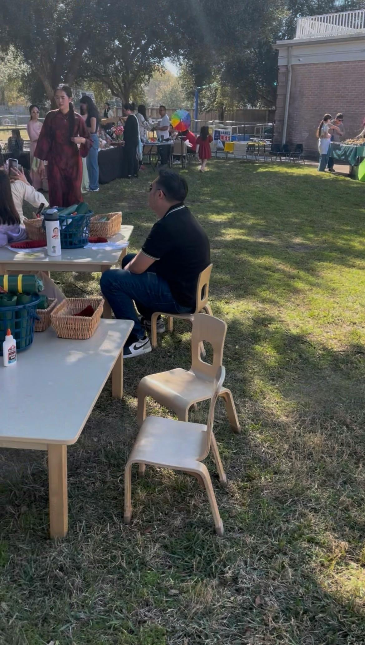 People gathered outdoors around tables and chairs on a grassy lawn