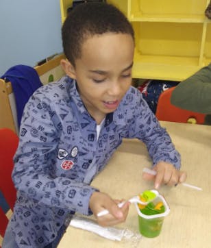 Child eating from a small cup with a spoon