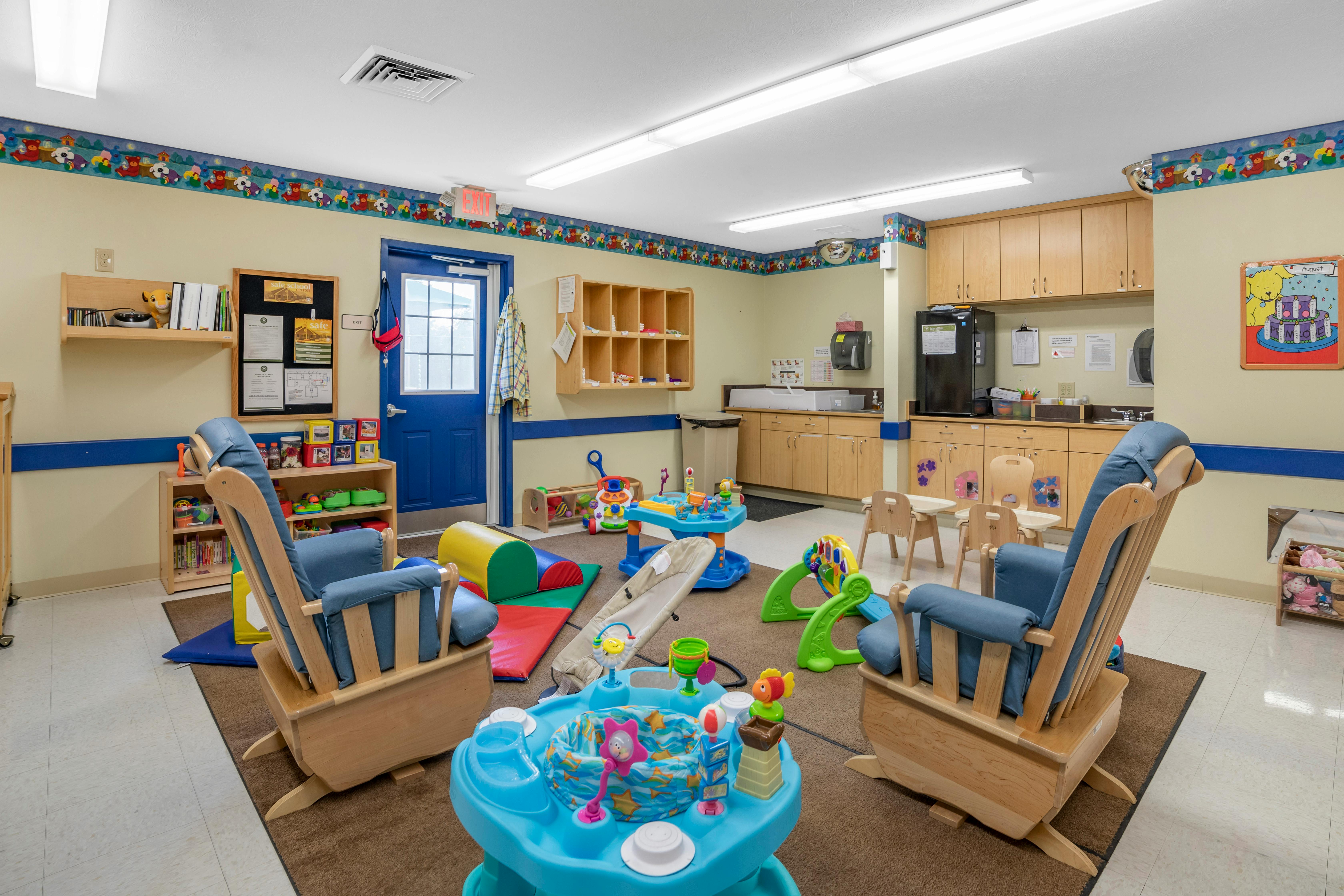 Childcare room with two wooden rocking chairs facing infant play equipment