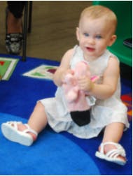 Child sitting on a rug holding a stuffed animal