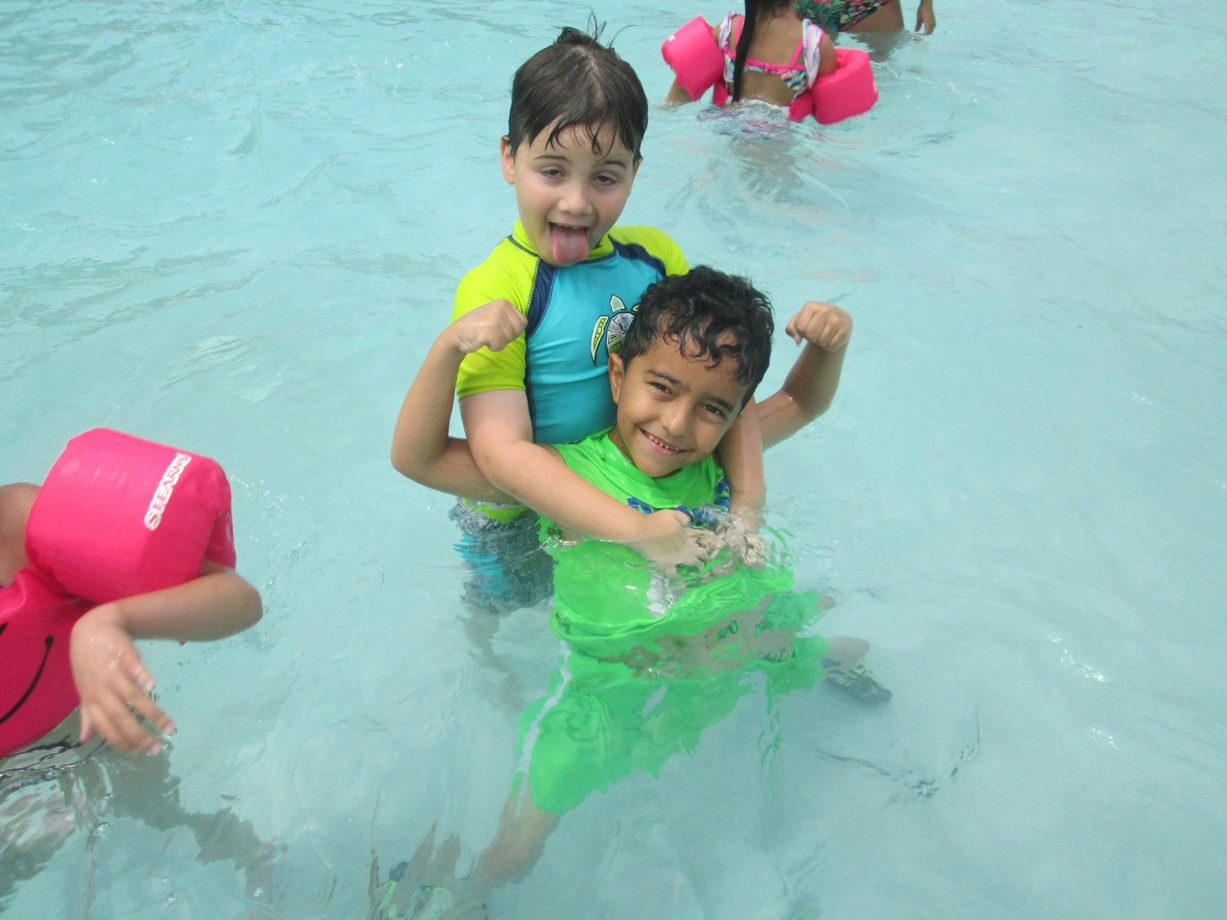 Two children in a pool, one holding the other