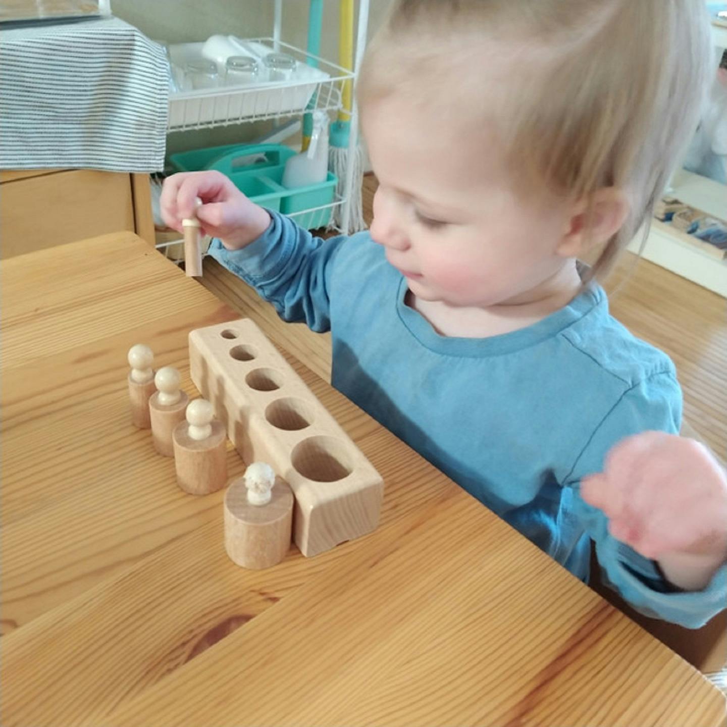 Child playing with wooden cylinder block puzzle on a table