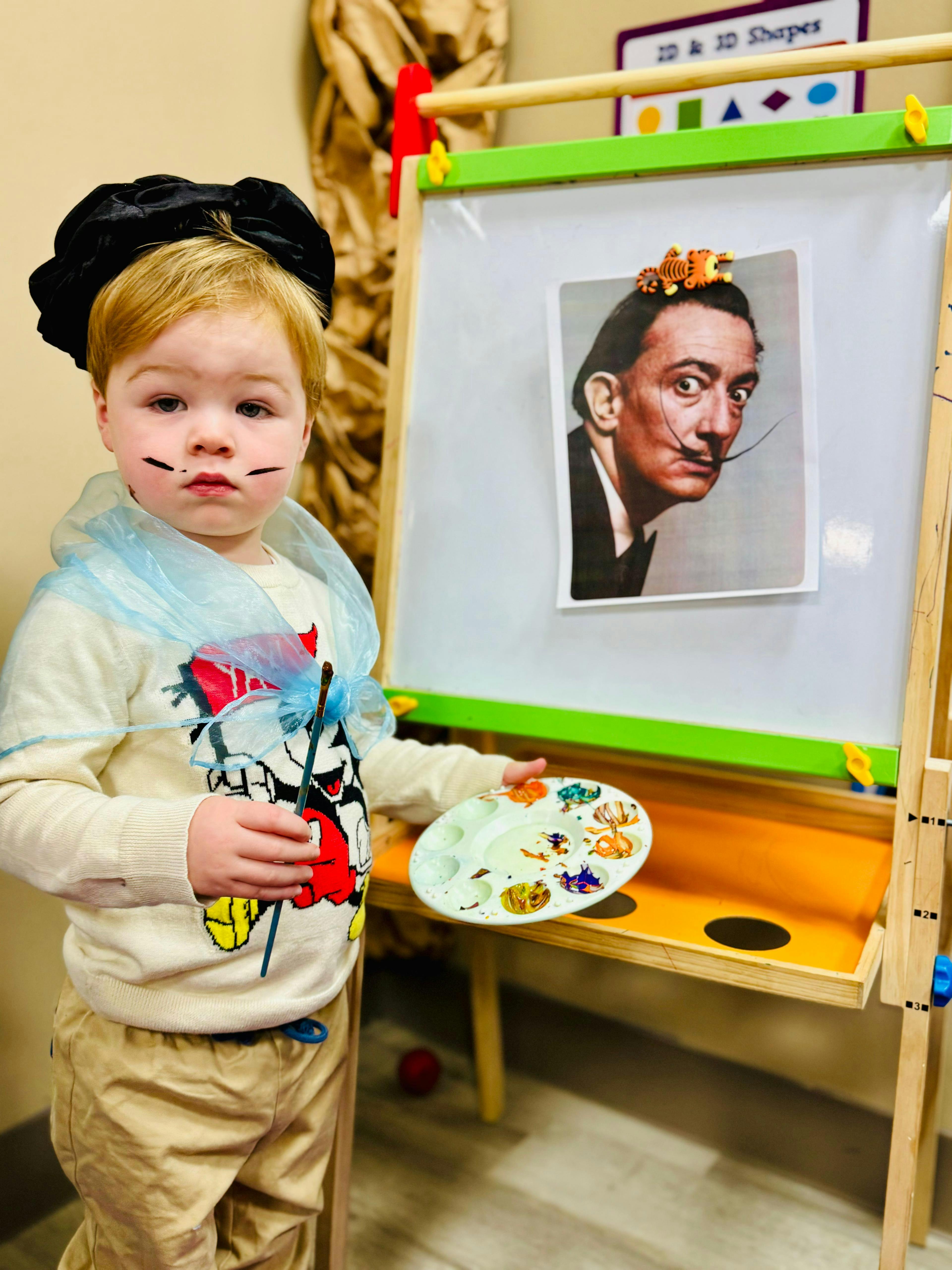 Child dressed as an artist holding a paintbrush and paint palette