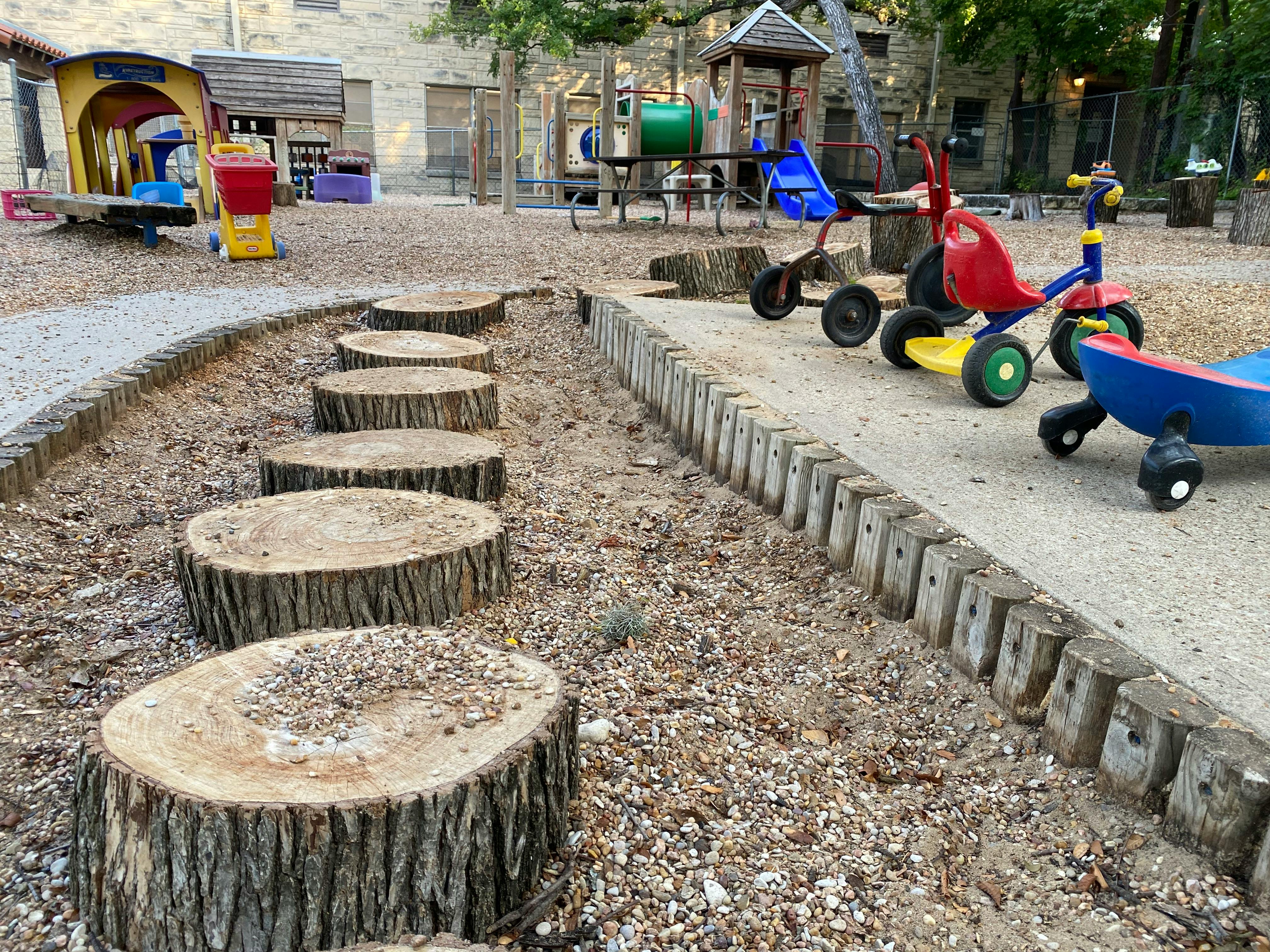 Tree stump stepping stones on a playground with tricycles