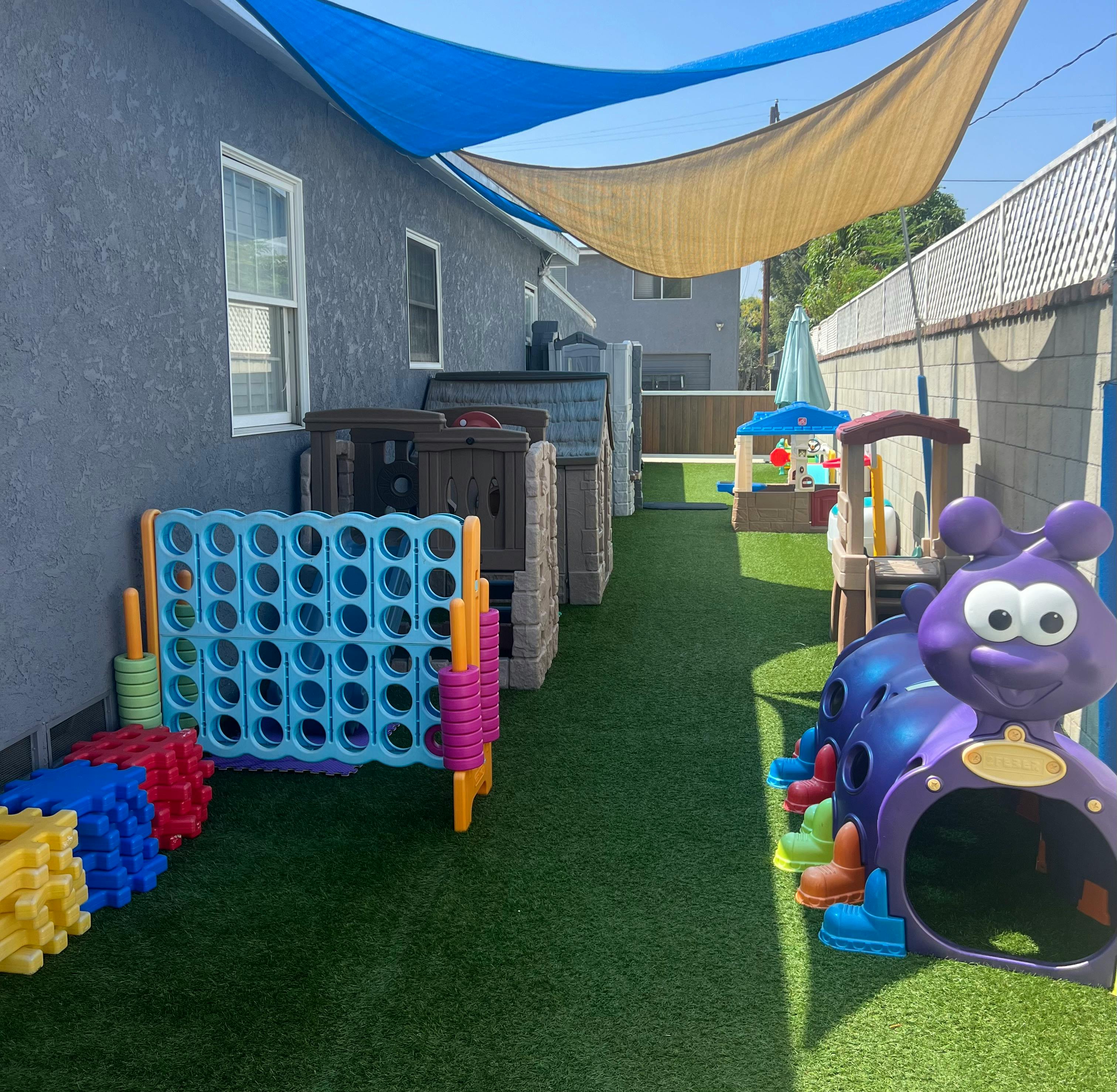 Outdoor play area with artificial turf, large Connect Four game, and play structures