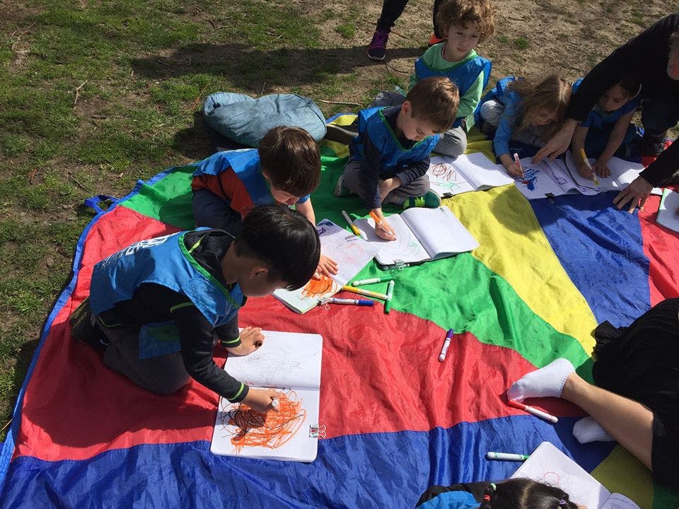Children drawing on a colorful blanket outdoors
