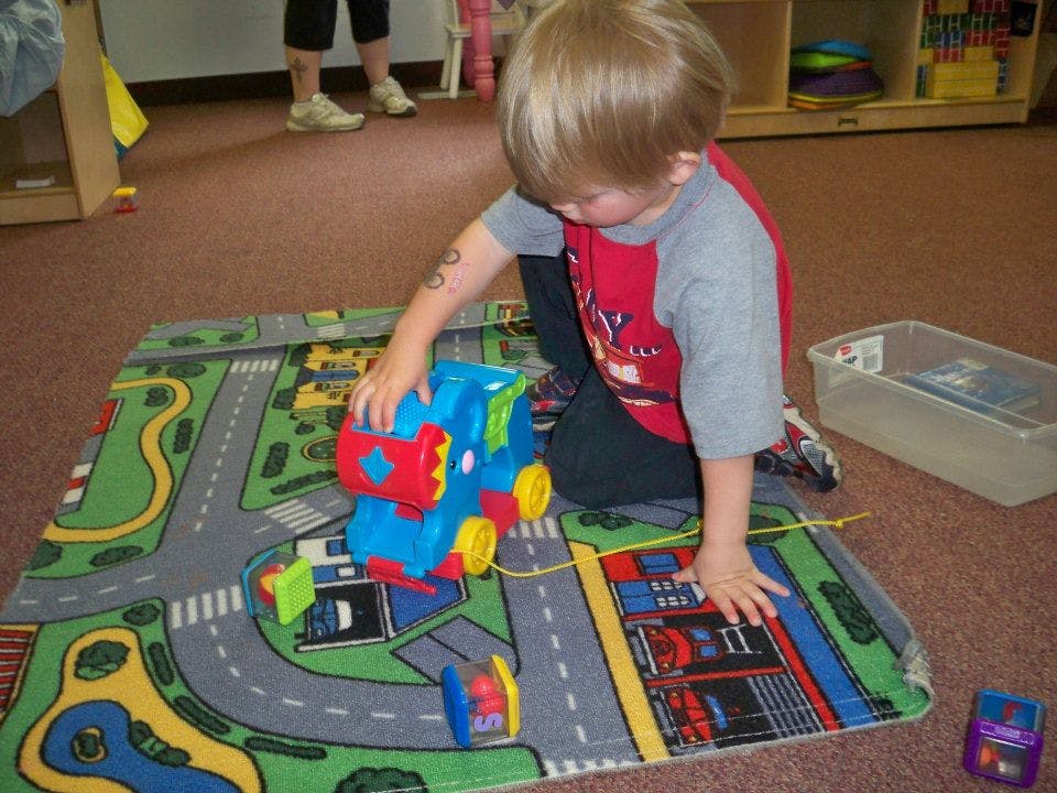 Child playing with a toy train on a road map rug
