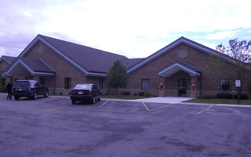 Brick building with gabled roofs and two cars in a parking lot
