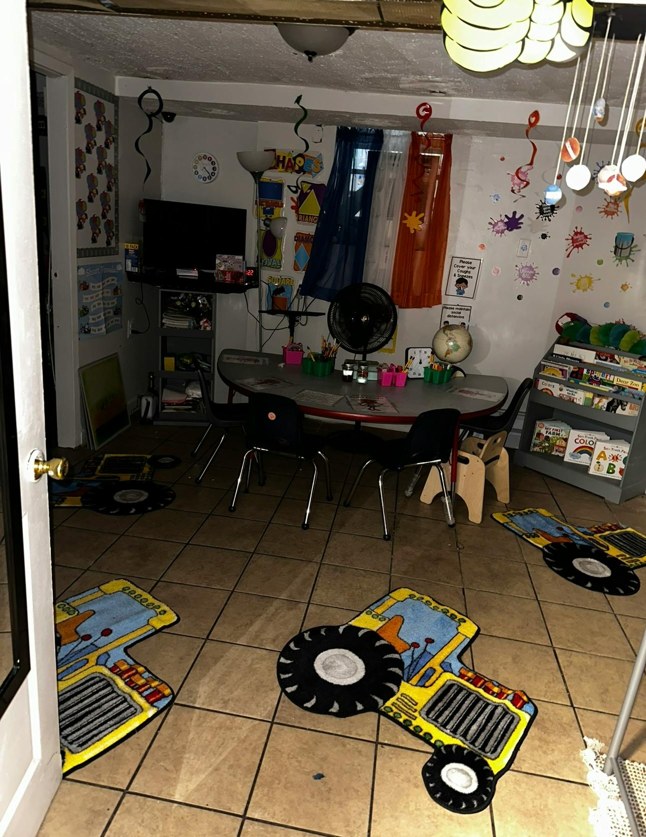 Playroom with small table and chairs, decorated walls, and tractor rugs on floor