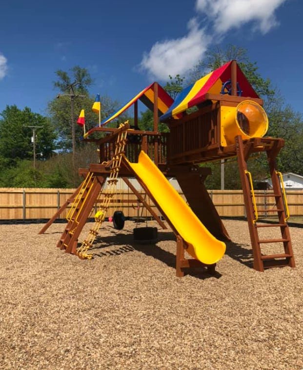 Wooden playground with yellow slide and colorful canopy