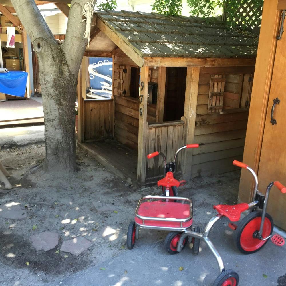 Wooden playhouse with two red tricycles in front