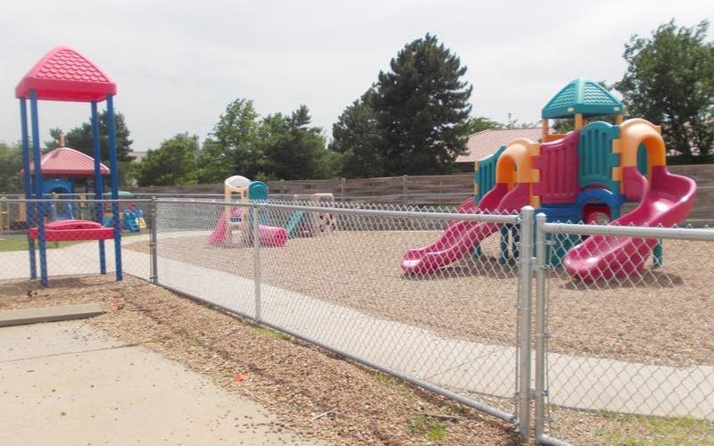 Playground with multiple colorful slides and play structures inside a chain-link fence