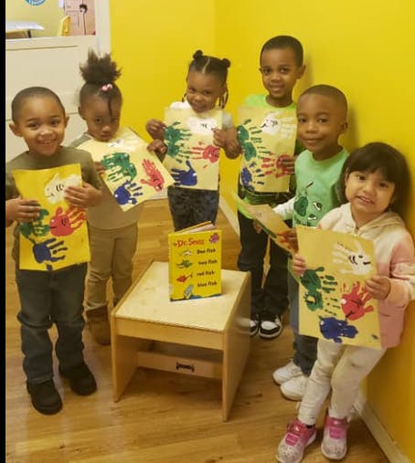 Group of children holding up artwork with colorful handprints