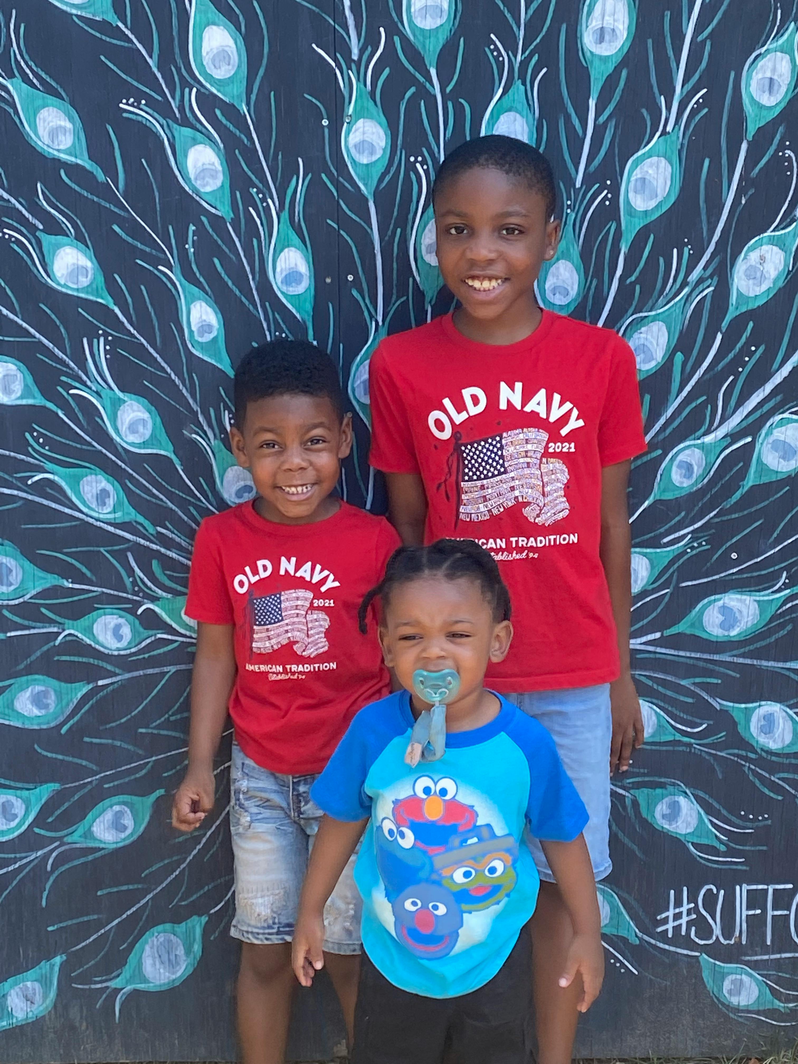 Three children standing in front of a painted wall