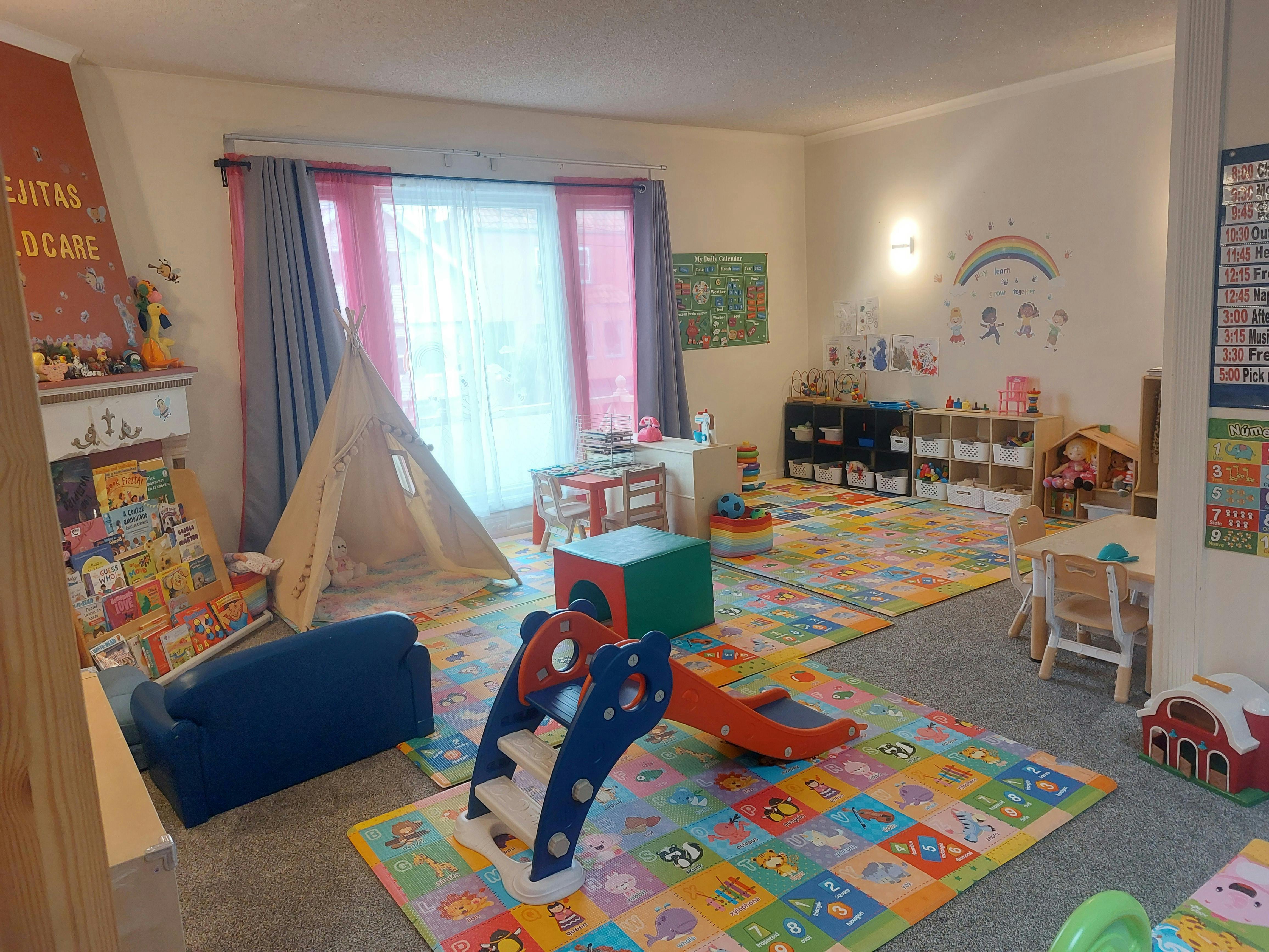 Playroom with colorful floor mats, a teepee, and a small slide
