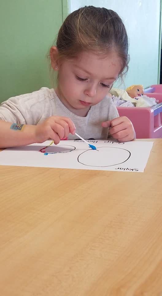 Child painting on paper with a cotton swab