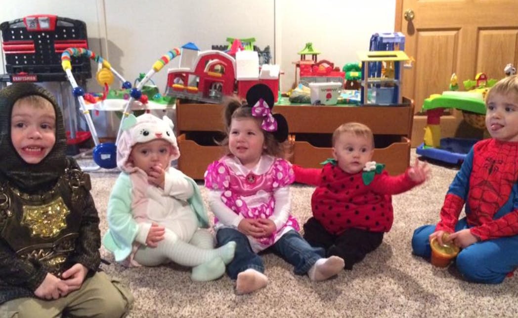 Five children sitting on a carpeted floor