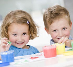 Two children playing with colorful paint pots