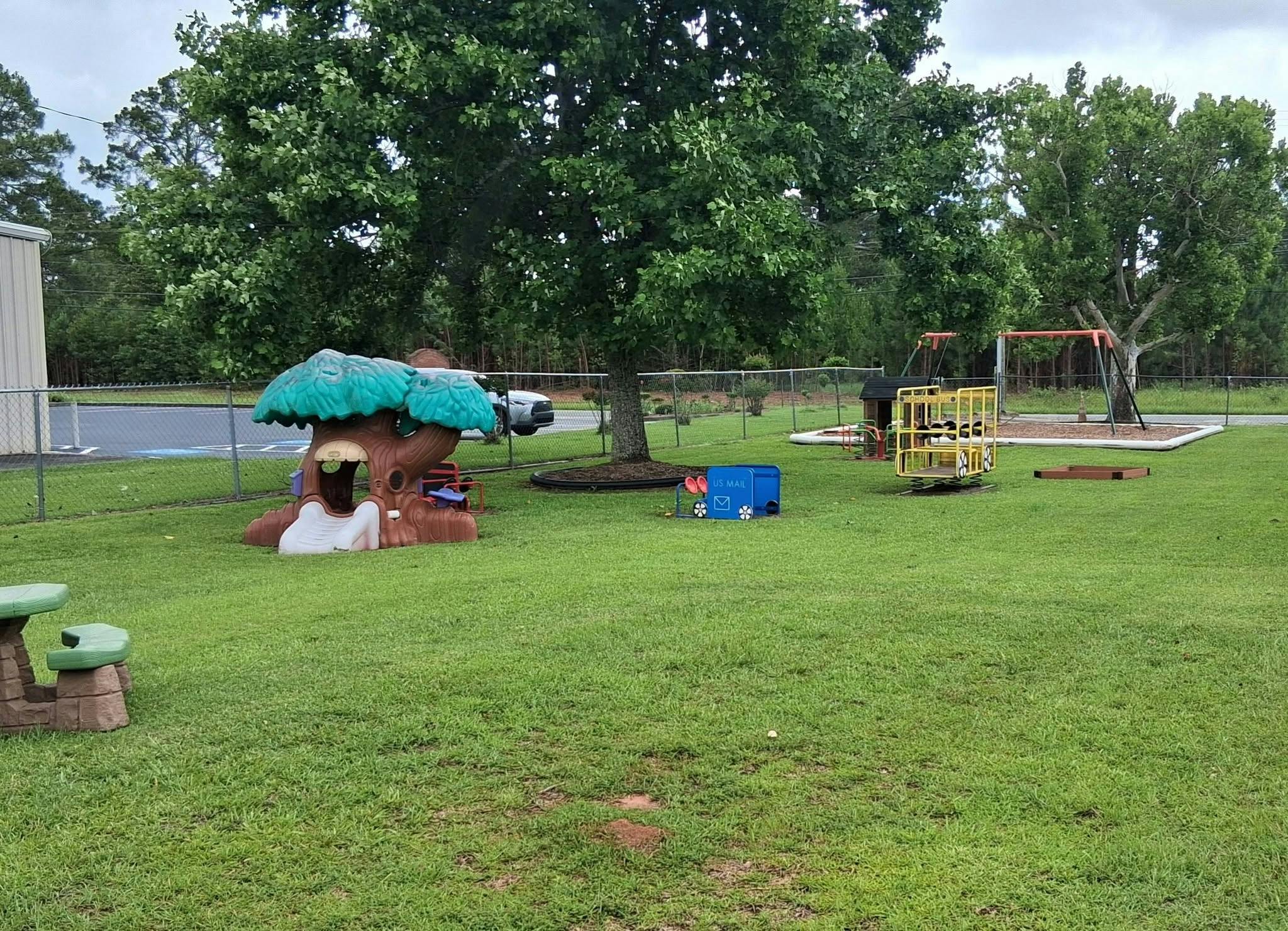 Playground equipment including a tree-shaped playhouse and a toy mail truck