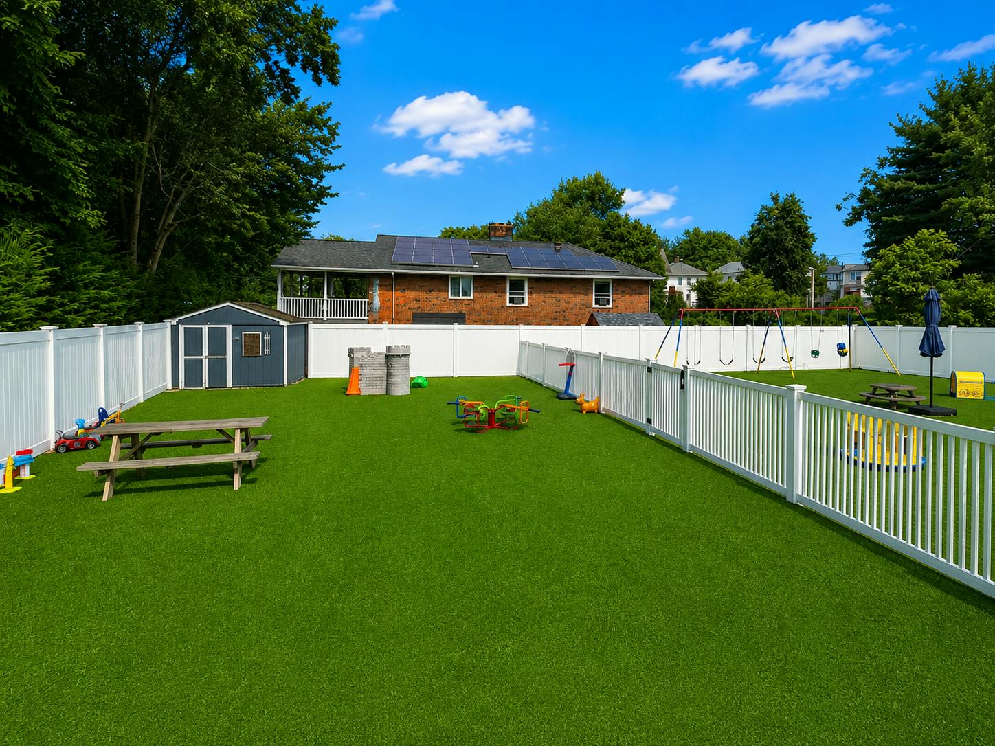 Backyard playground with synthetic grass, swing set, and picnic table