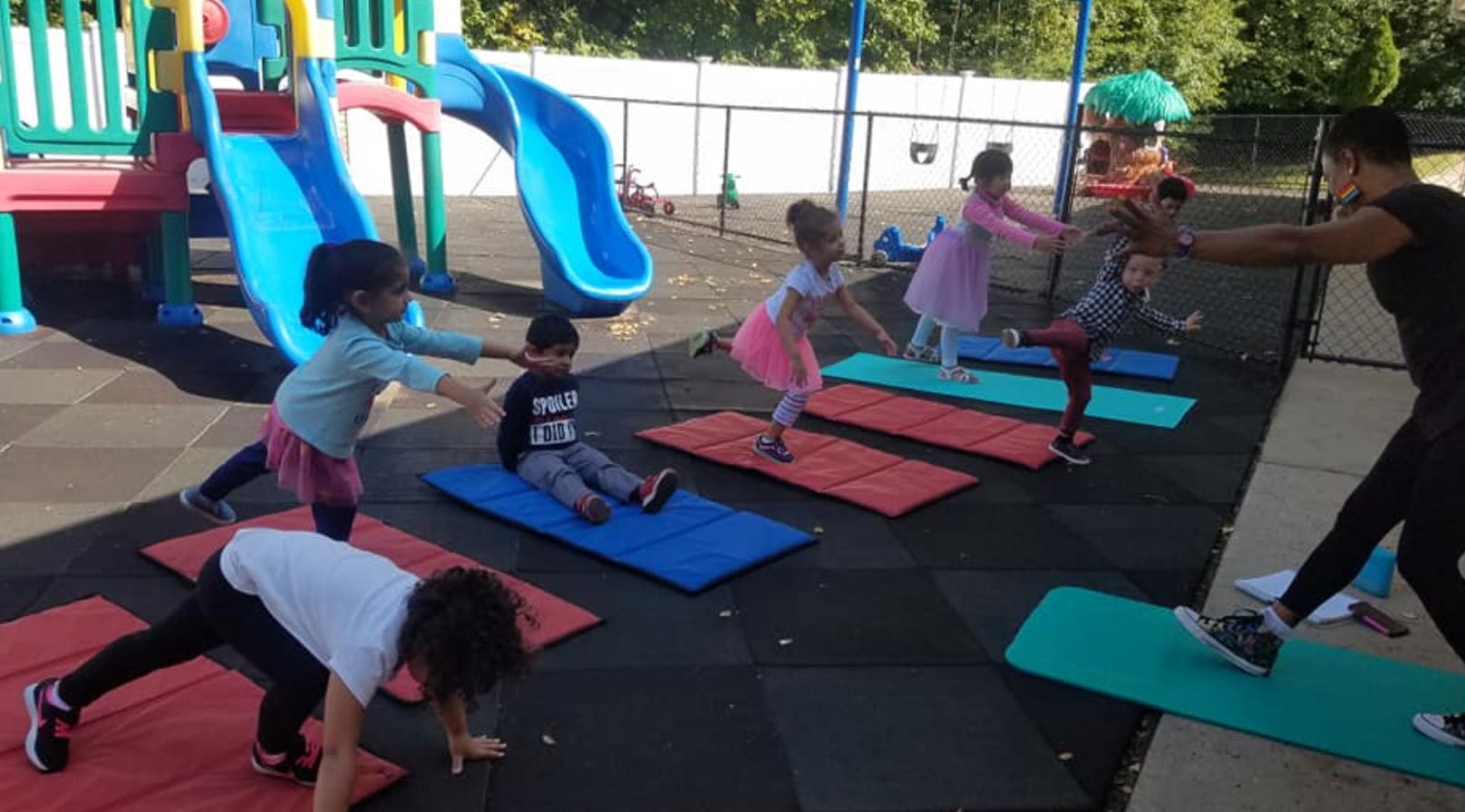 Adult and children exercising on mats outdoors