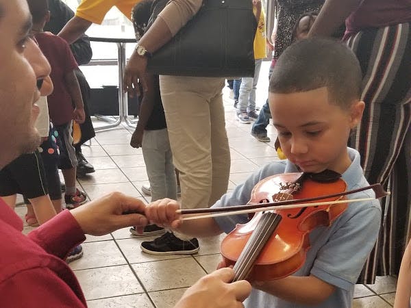 Person helping a child play a violin