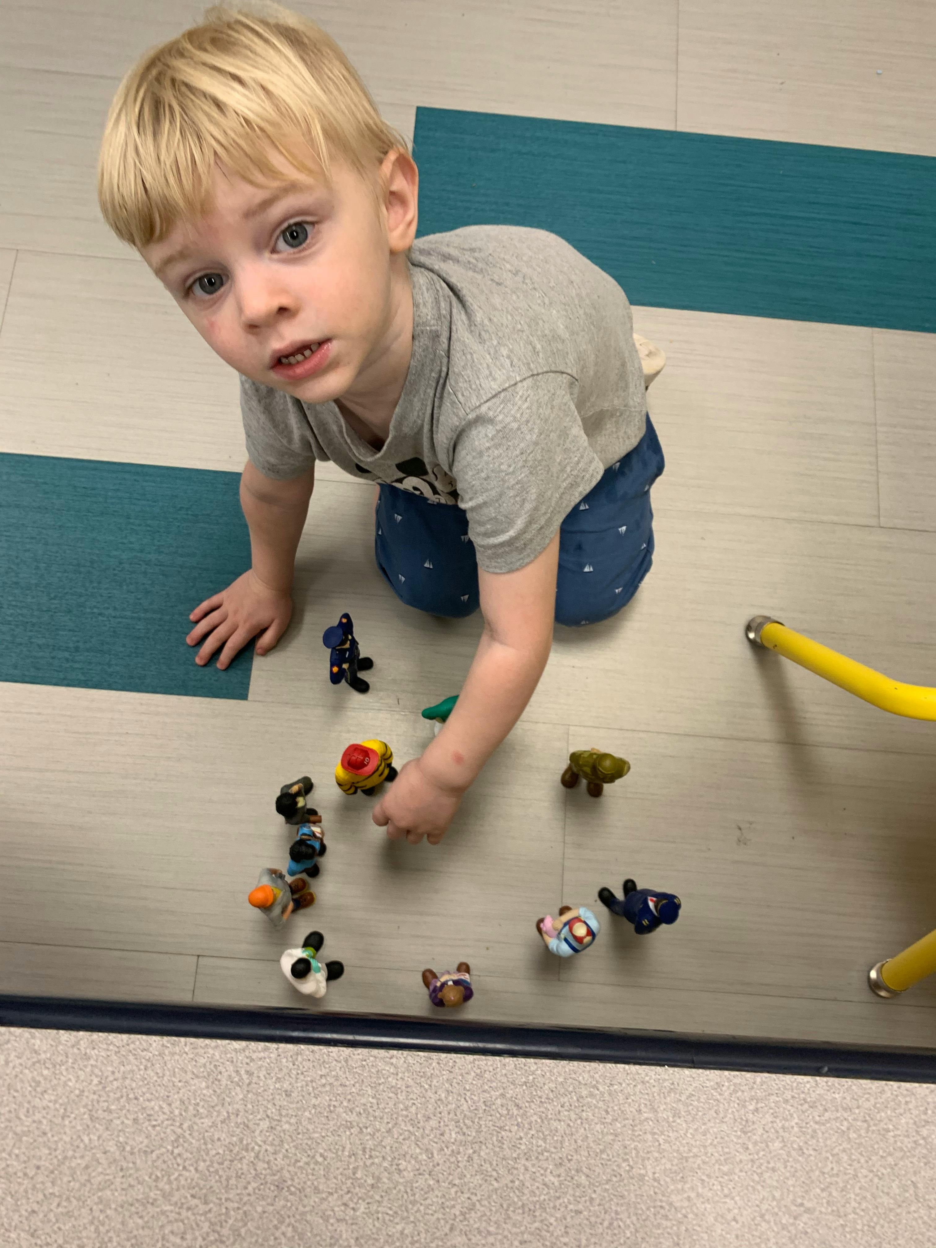 Child on knees playing with small toys on the floor