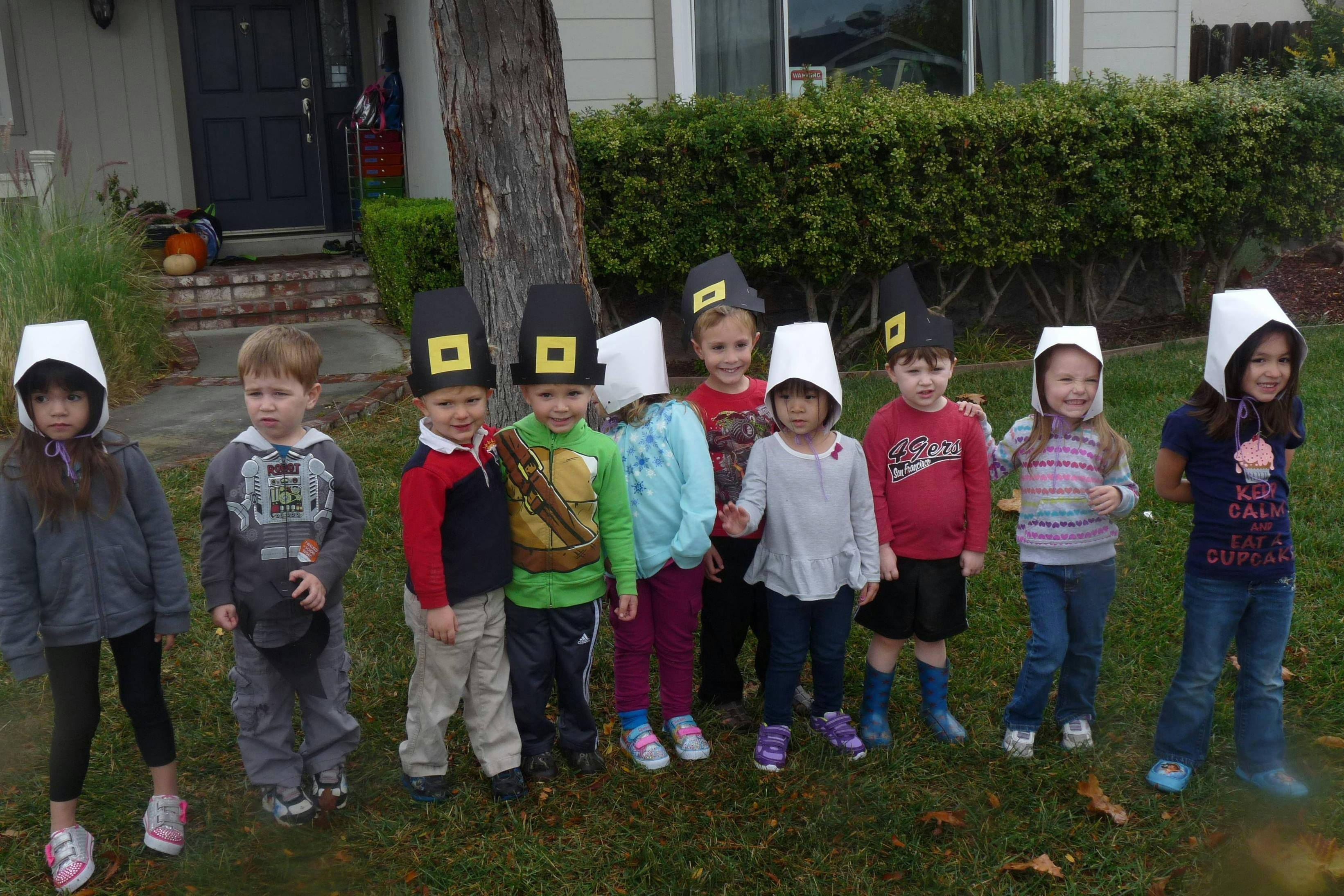 Group of children wearing pilgrim and Native American hats outdoors