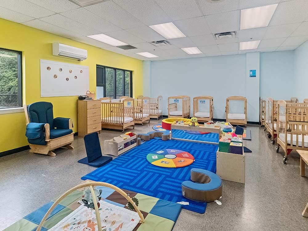 empty daycare room with cribs and play area