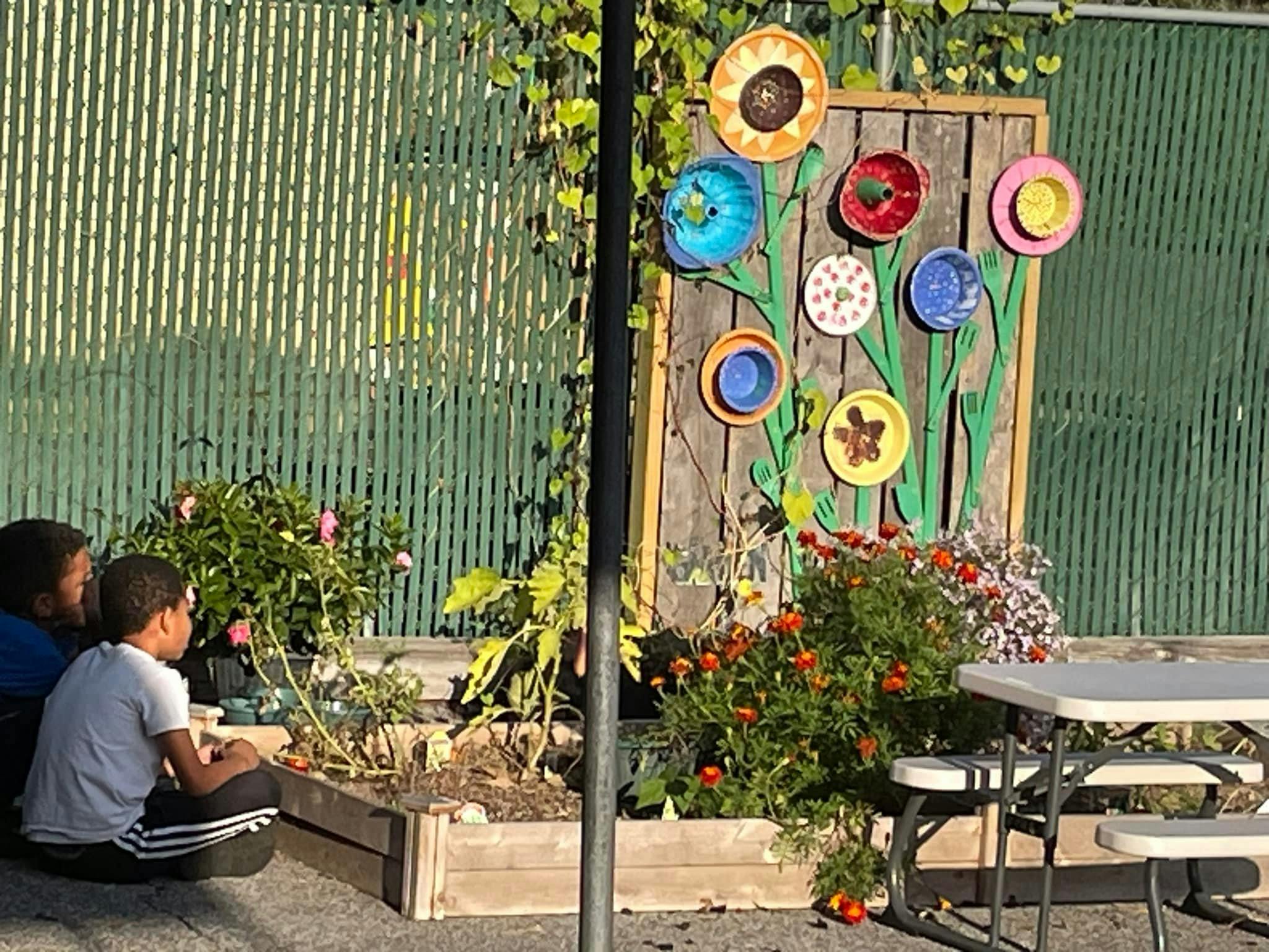 Two children sitting by a raised garden bed with flowers