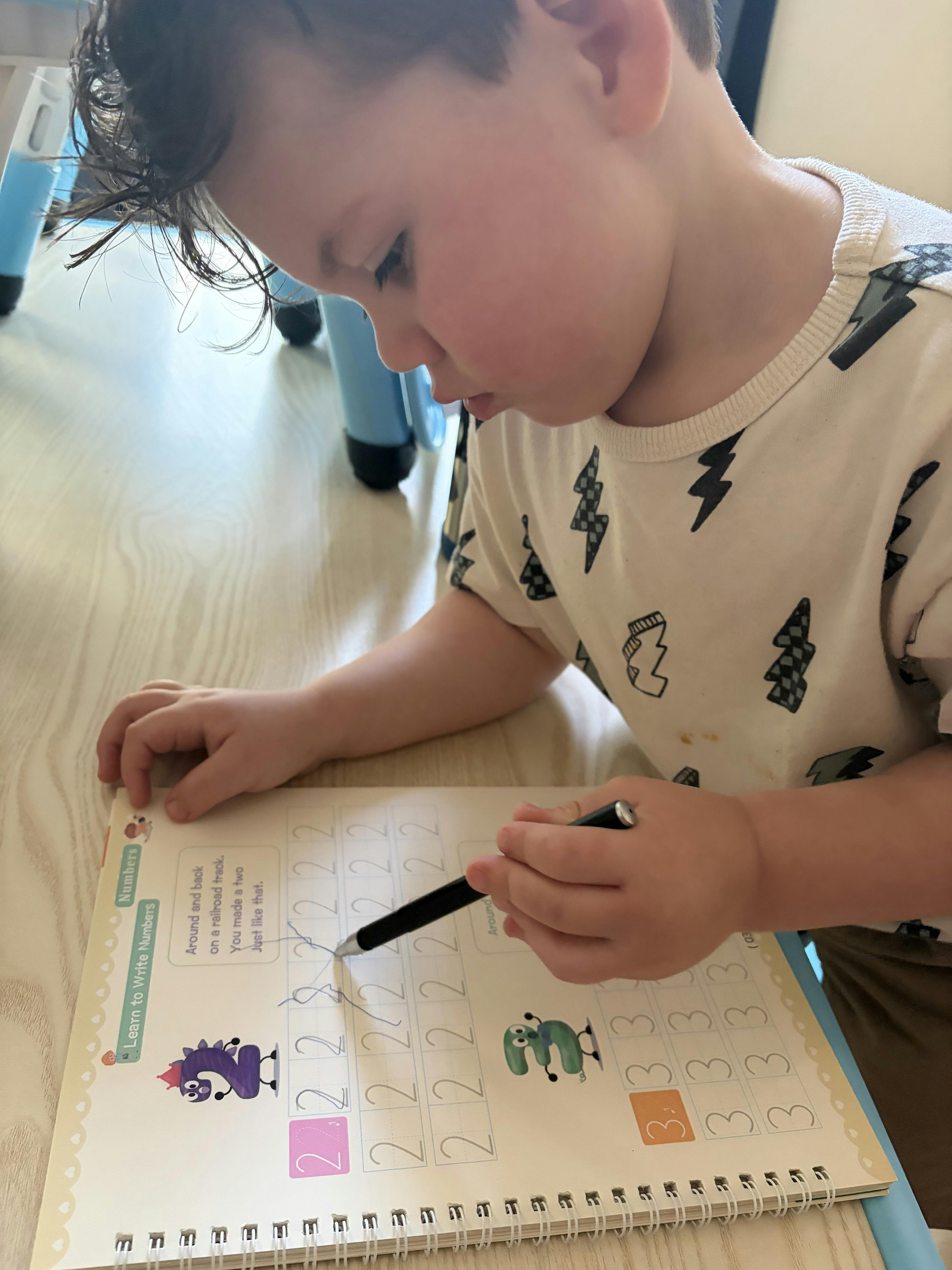 Child learning to write the number two in a workbook