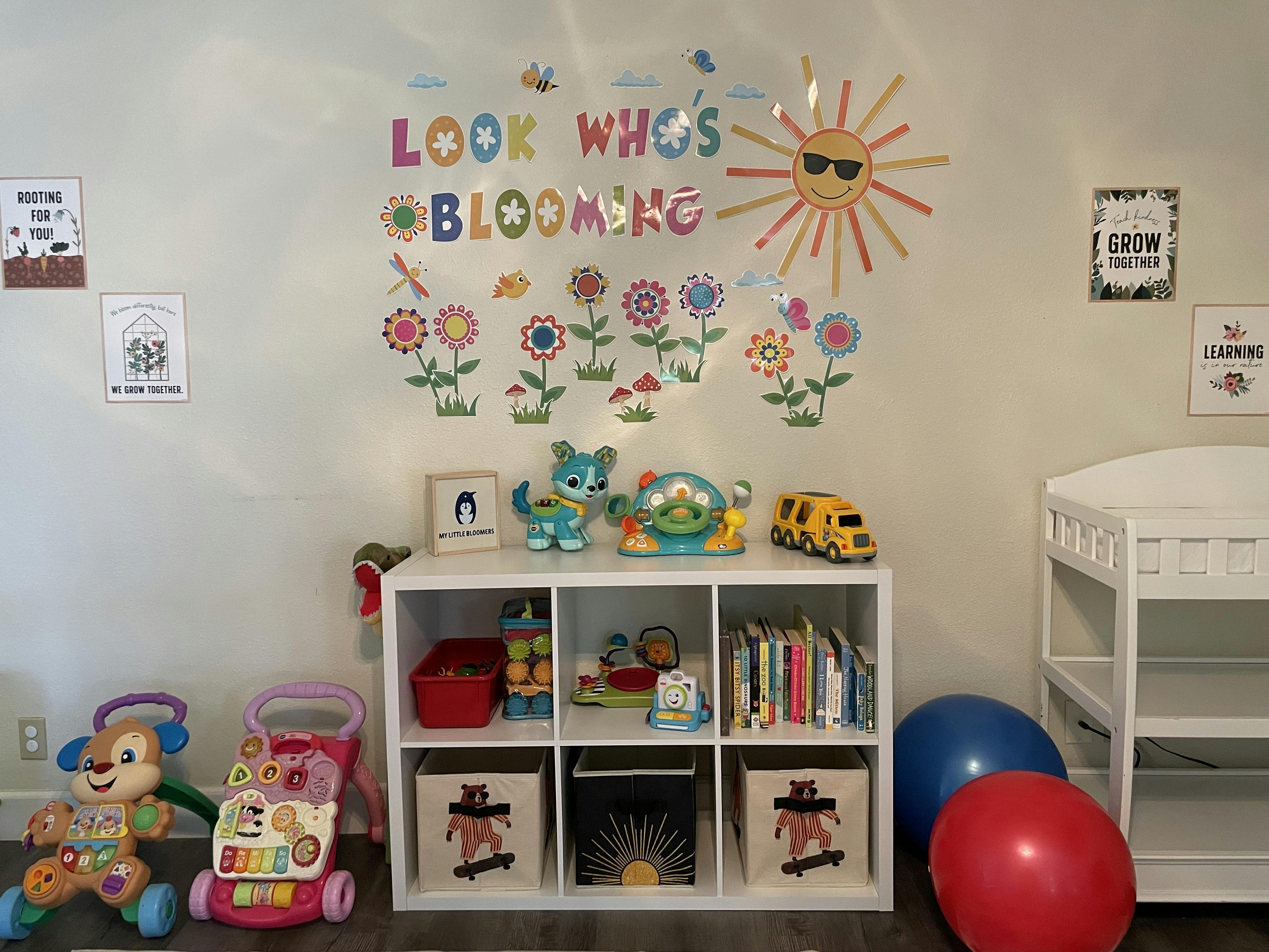 Playroom wall with Look Who Is Blooming sign and toy storage cubby