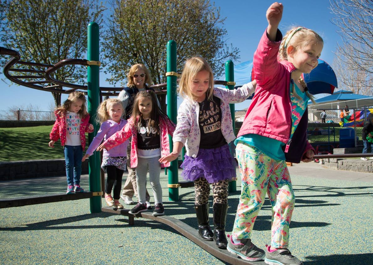Children walking on a balance beam on a playground