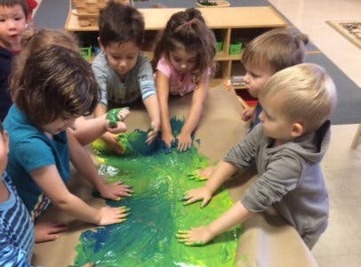 Children finger painting with green and blue paint