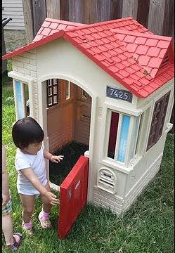 Child opening the door of a playhouse