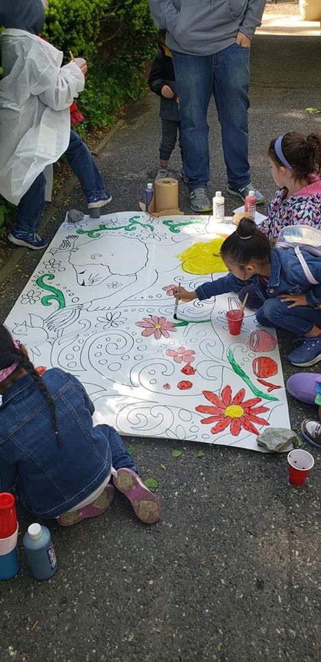 Children painting a large mural on the ground outdoors