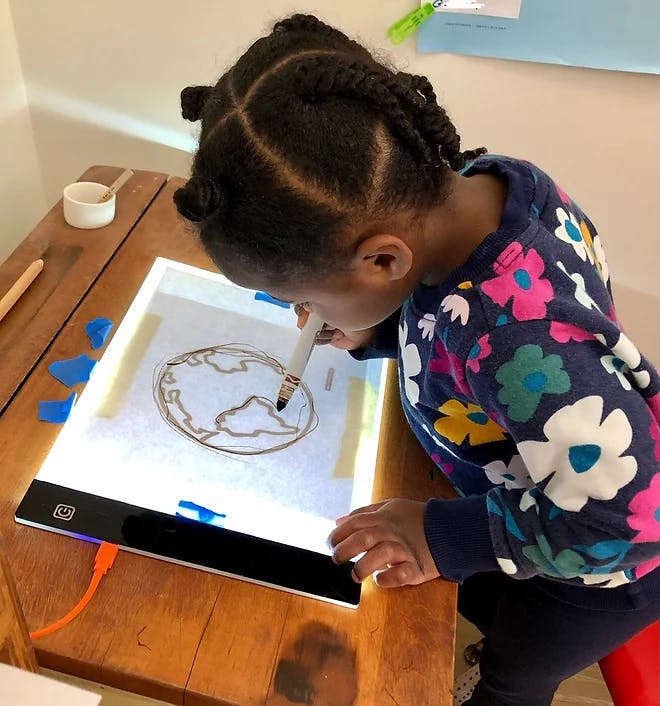 Child drawing on a light board