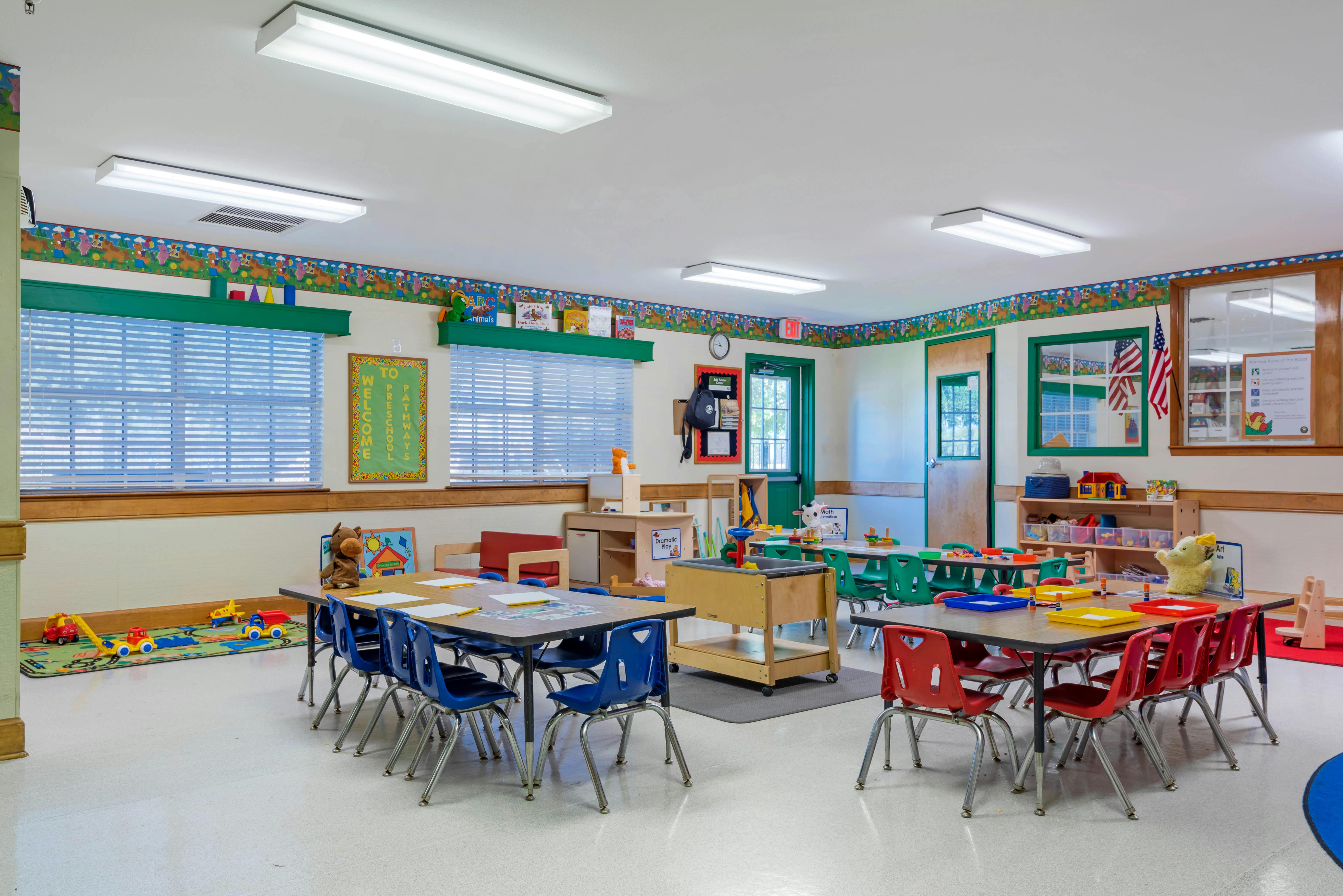 Empty preschool classroom with tables, chairs, and toys