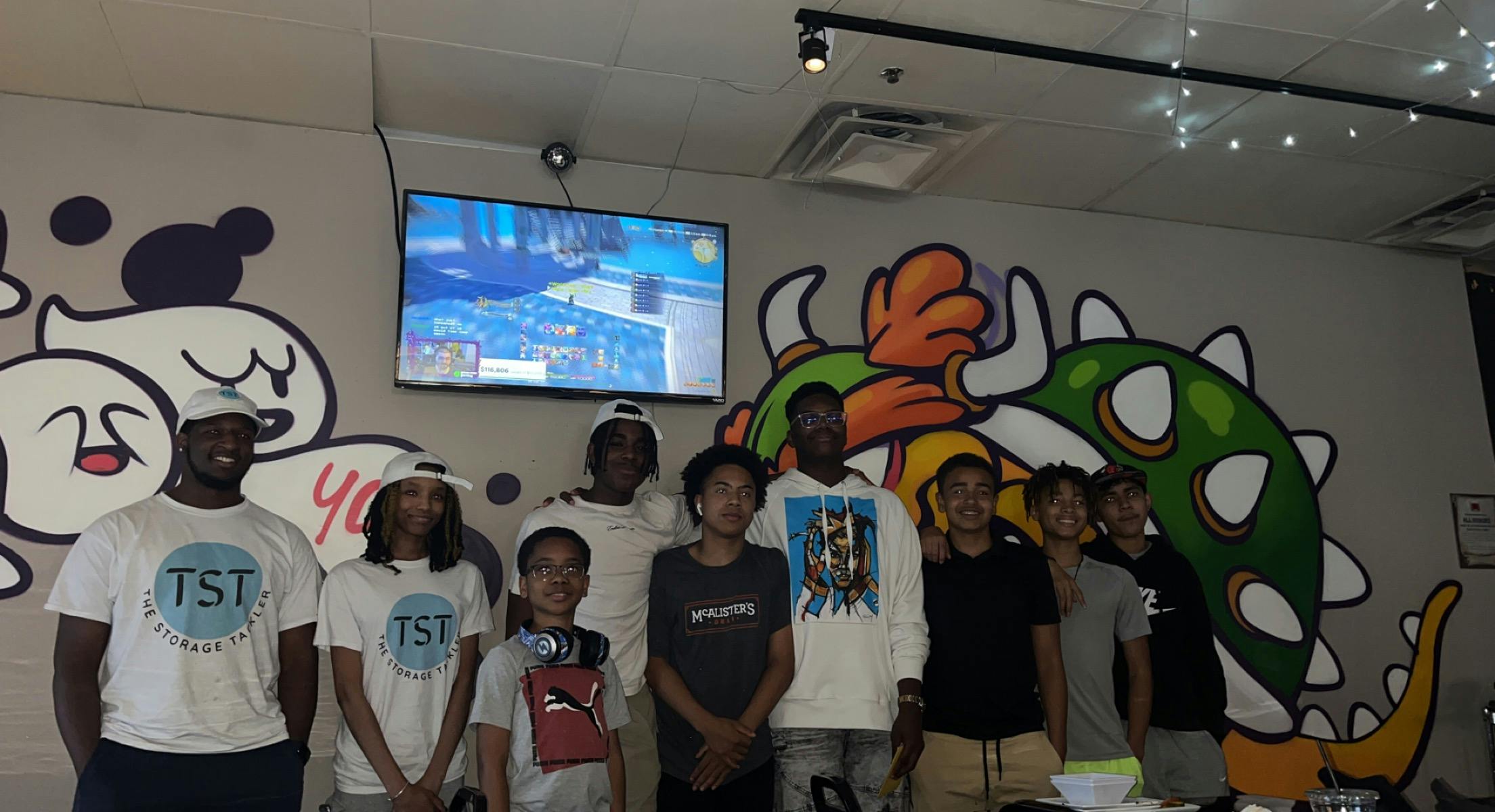 Group of people standing in front of a wall with cartoon murals and video game art