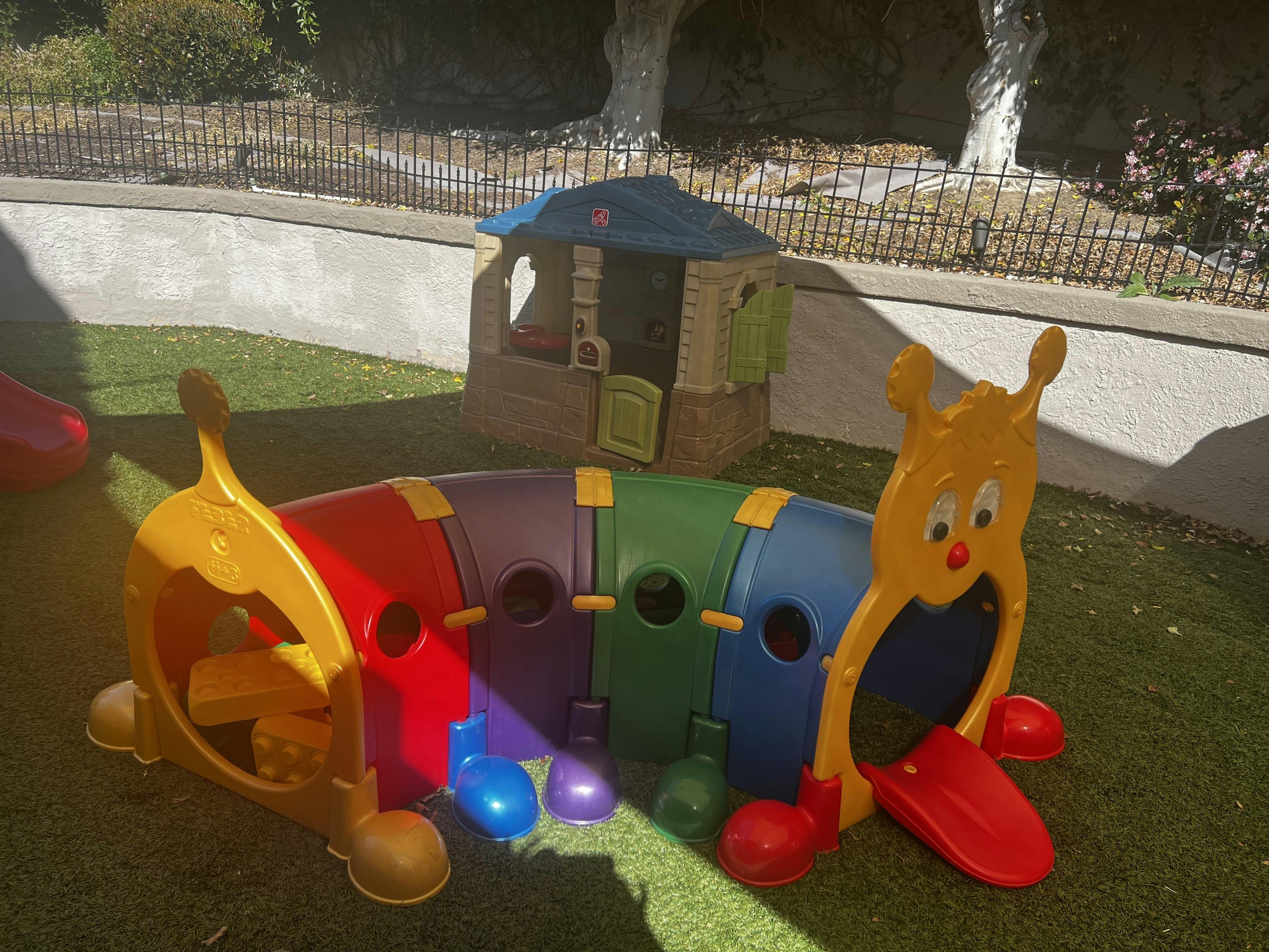 Colorful caterpillar tunnel and playhouse on grass