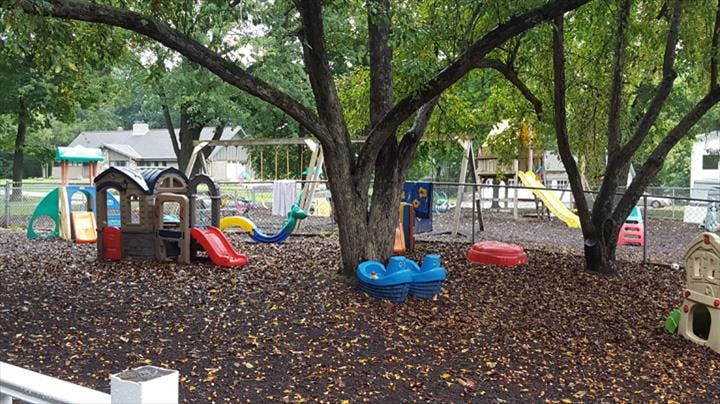Outdoor playground with slides, swings, and play structures under trees