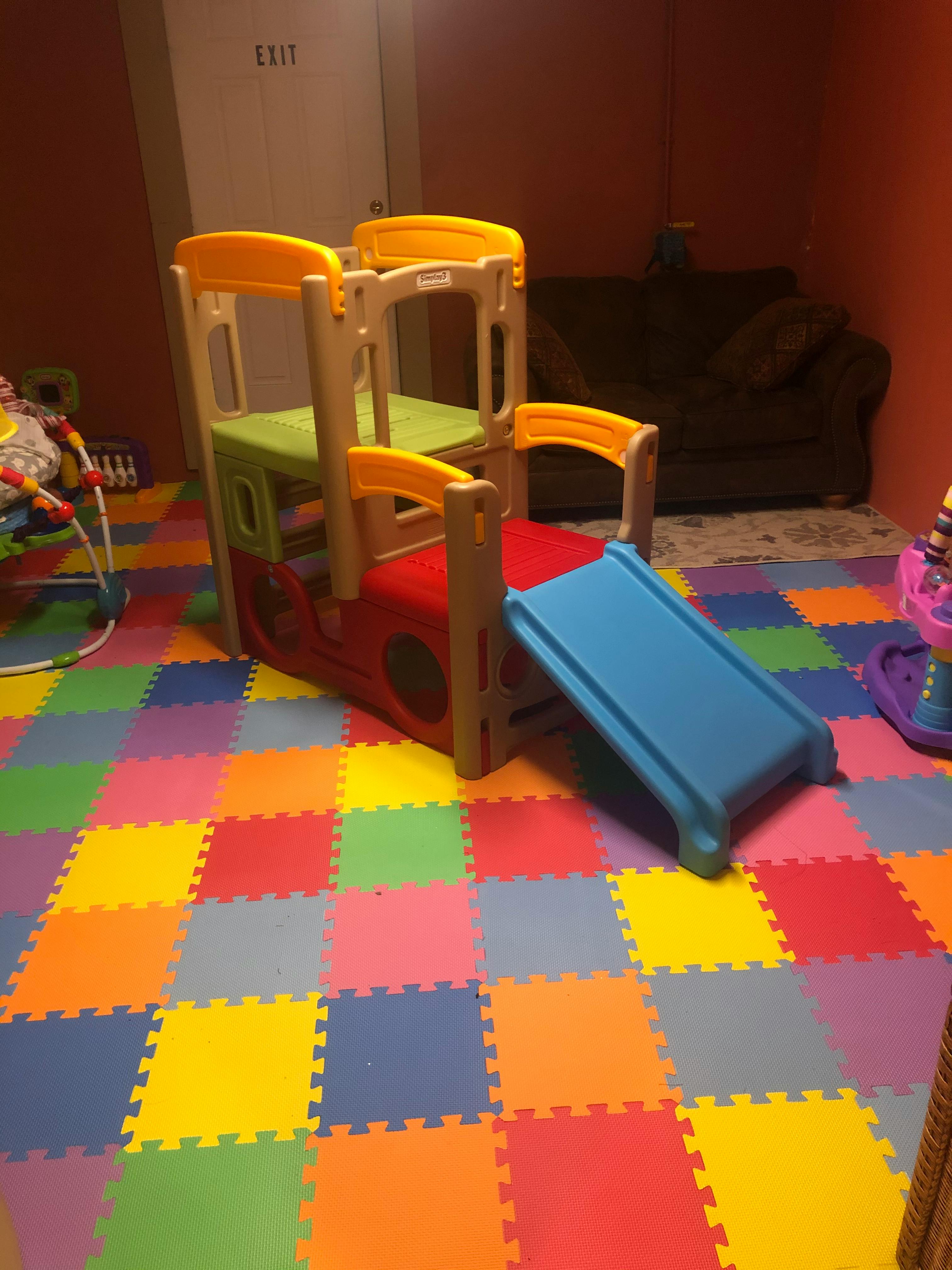 Indoor play structure with slide on a colorful foam mat