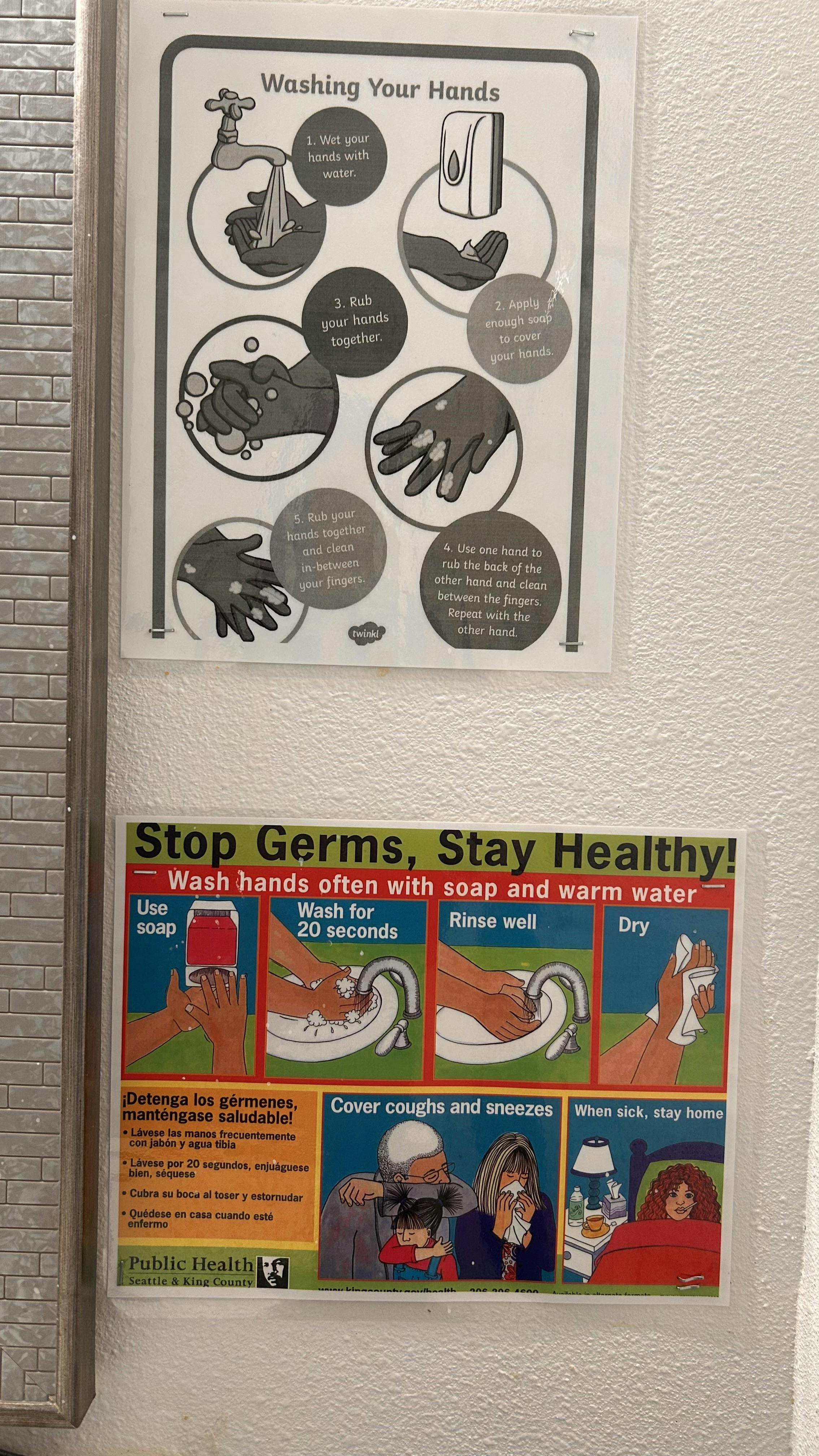 Two posters on a wall, one about washing hands and another about staying healthy