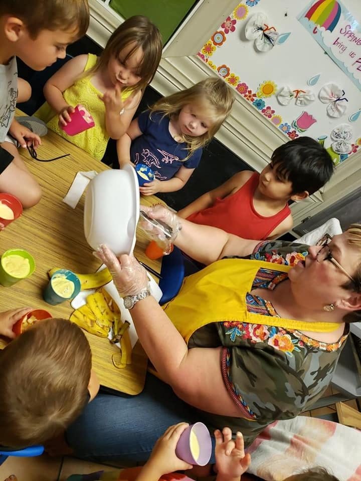 Adult and children gathered around a table with cups and bowls