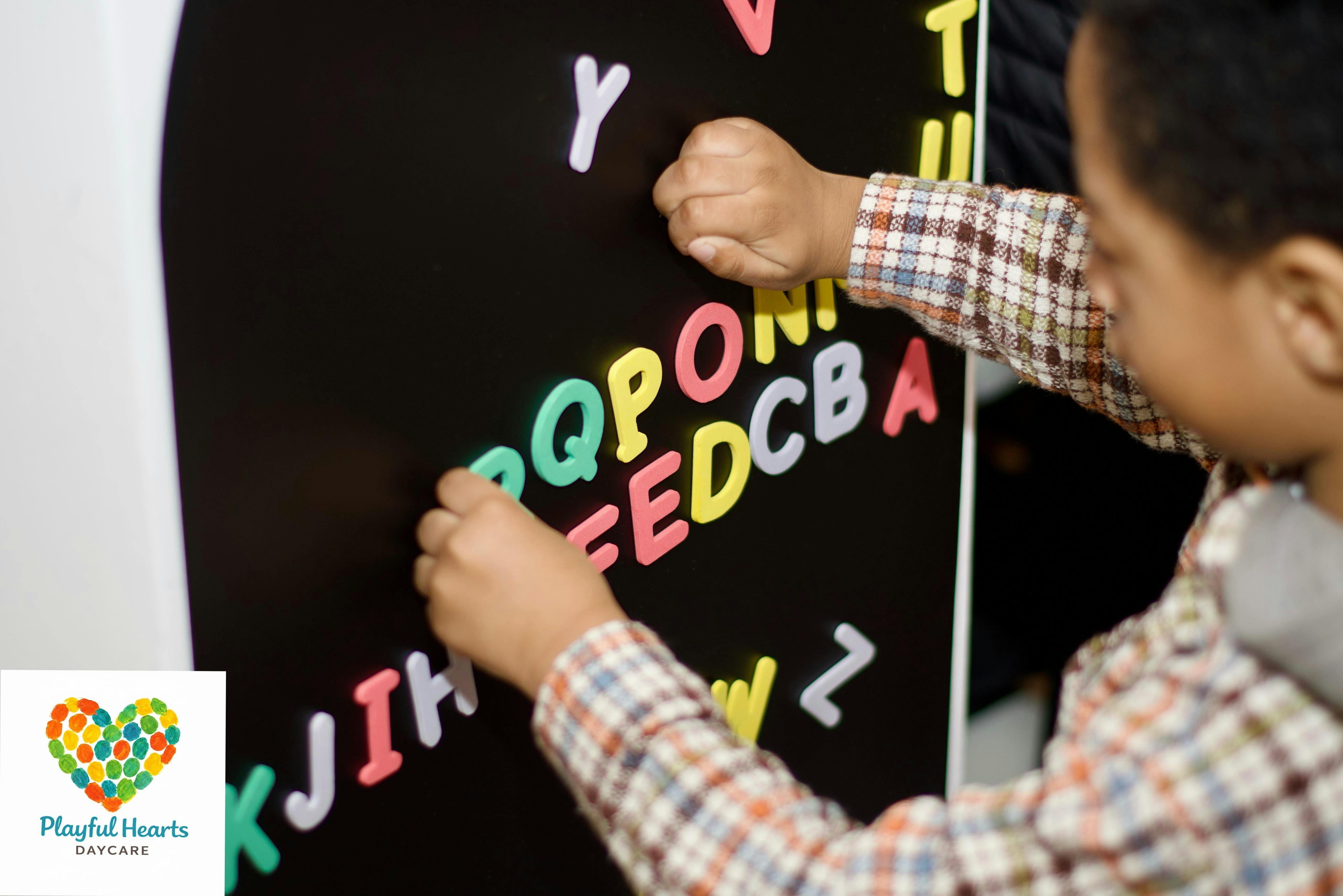 Child's hands playing with colorful magnetic letters on a black board