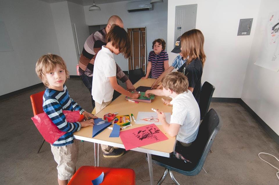 Adult and children gathered around a table with art supplies
