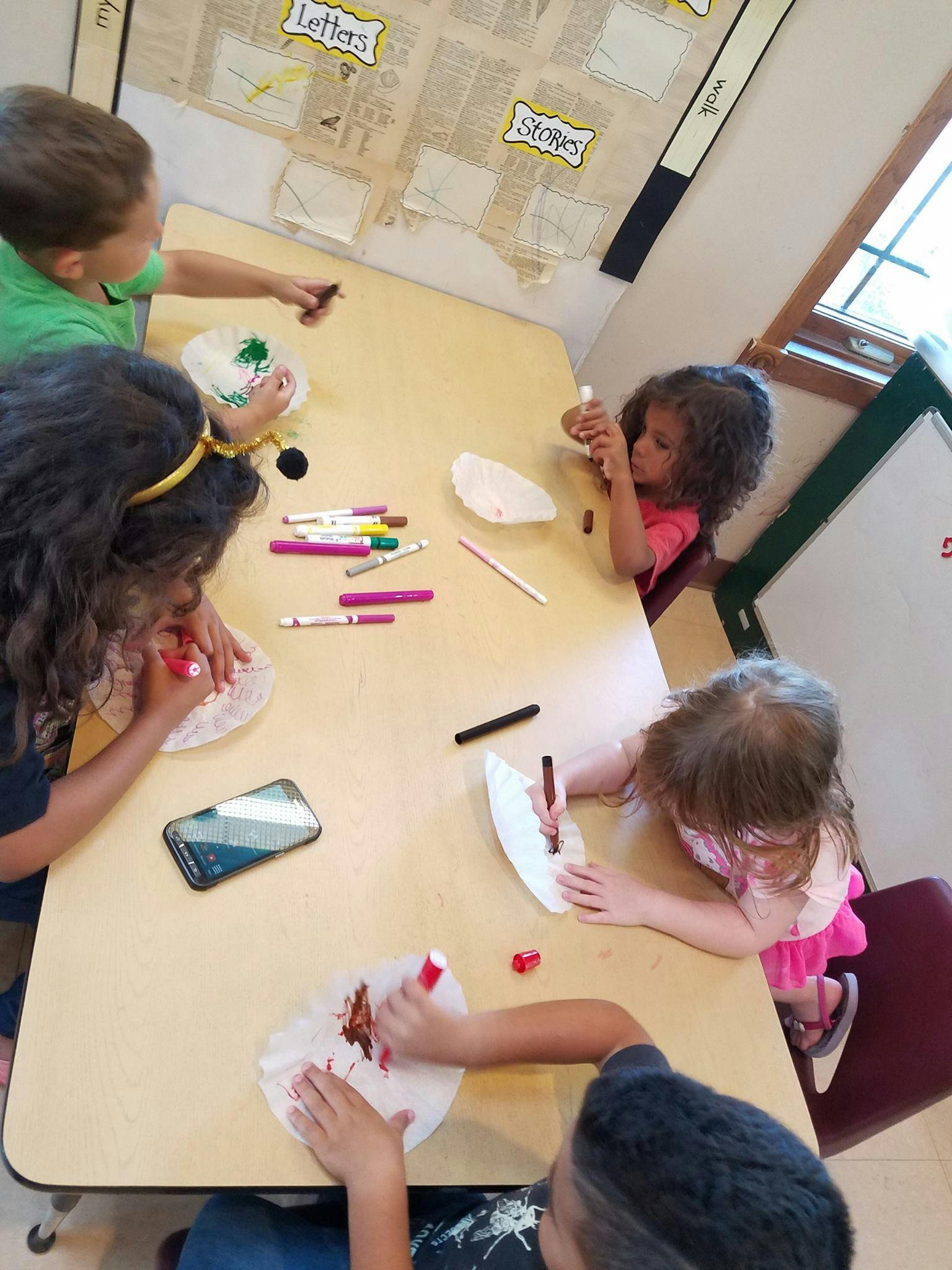 Children coloring paper plates at a table