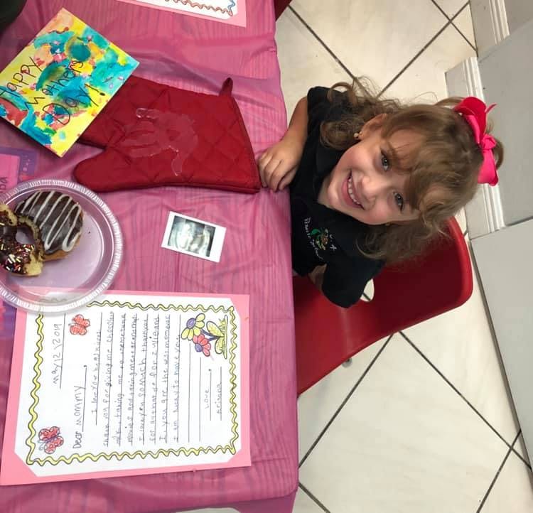 Child sitting at a table with donuts and a drawing